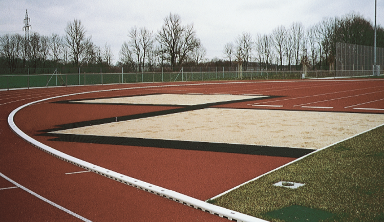 Canal LW125 con reja de plastico y arenero en una pista de atletismo